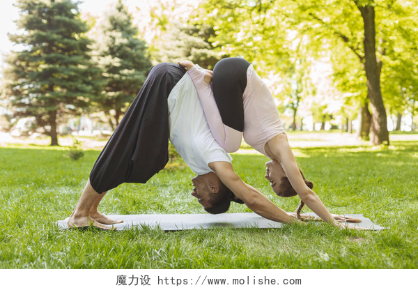 年轻夫妇练习瑜伽一起瑜伽。一对年轻人在户外练习杂技